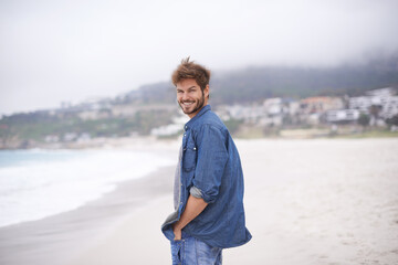 Portrait, beach and man with a smile, vacation and summer holiday with weekend break and water. Waves, face and person with happiness and guy with seaside and travel with peace and wind with nature