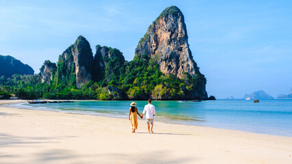 Obraz premium a couple of men and women relaxing on the beach during a vacation in Thailand Railay Beach Krabi with beautiful limestone cliffs in the background