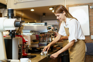 Good looking female barista using a tamper pressing on grounded coffee, woman is preparing to make an expresso coffee. - obrazy, fototapety, plakaty