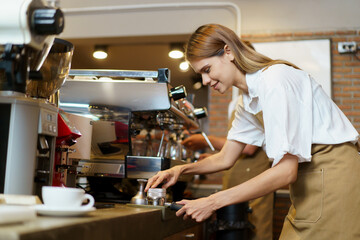 Good looking female barista using a tamper pressing on grounded coffee, woman is preparing to make an expresso coffee.