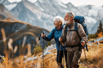 Senior pensioner couple with nordic walking poles hiking in the mountains
