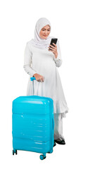 Beautiful muslim woman looking at mobile phone with a suitcase