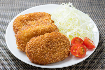 コロッケ(平たい小判型のポテトコロッケ)。
