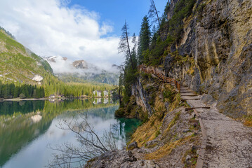Fototapeta na wymiar beautiful landscape of mountain lake Braies in the Dolomites, Italy. Hiking trail along the lake and low clouds over the mountain