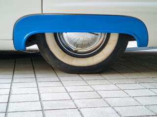 Classic vintage car - rear wheel of old white and blue retro American car.