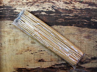 Top view of wooden skewers in the plastic on the wooden board. 