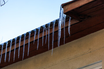 Large icicles on the roof pose a danger to passersby. Background with selective focus and copy space