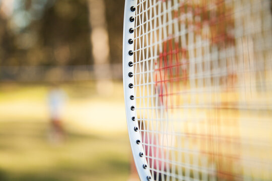 Badminton racquet with game happening behind out of focus