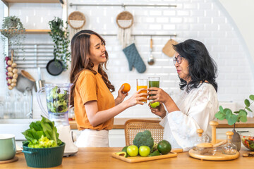 Young woman and elderly mother in healthy lifestyle, glass with nutritious beverages, daughter hold...