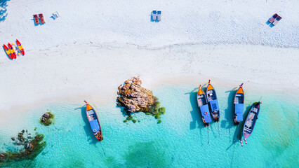  top view at longtail boats on the beach of Koh Lipe Island Thailand, tropical vacation background, colorful turqouse colored ocean drone view