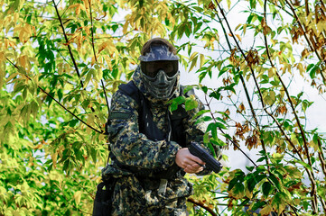 military man with a pistol in his hands, in camouflage uniform, protective mask and goggles