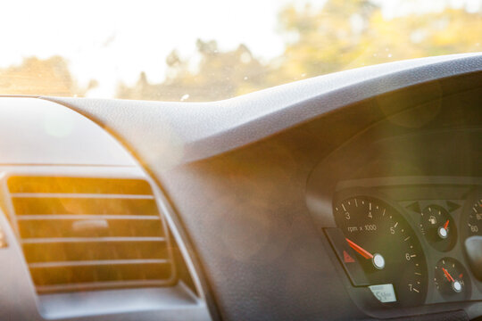 Golden sun flare over air con vent and speedometer of car