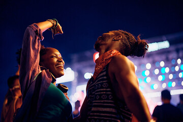 Young black couple having fun while dancing on open air summer festival at night.