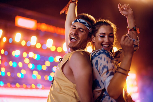 Carefree couple having fun while dancing on open air music concert at night.