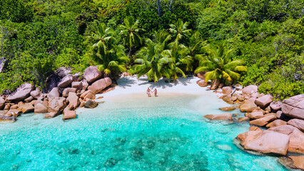 top view at a couple of men and women on vacation at Seychelles visiting the tropical beach Anse Lazio Praslin Seychelles. drone view at a tropical lagoon with turqouse colored ocean and palm trees