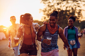 Cheerful multiracial couple having fun on summer music festival at sunset.