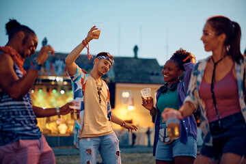 Multiracial group of happy friends dancing on summer music festival.
