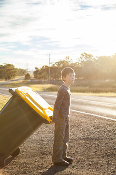 Young boy doing job taking bin across the road