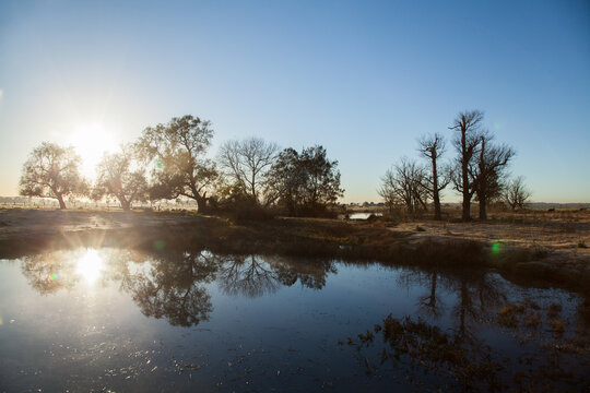 Double sunrise reflected in a farm dam