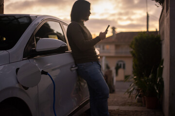 A man is charging an electric car parked in the house area.