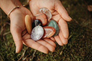 Woman hands holding healing gem stones on green moss