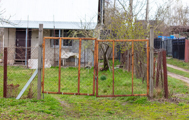 Fototapeta na wymiar Gate on a wooden fence made of metal mesh