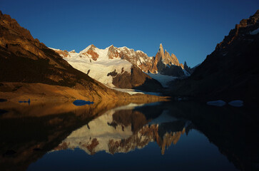 Granite mountain peaks and glaciers of Cerro Torre and the Adela Range are reflected in the calm waters of Laguna Torre in the morning light, Southern Patagonian Ice Field in South America, Argentina