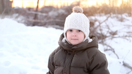 Portrait of smiling little toddler boy. Winter season. Warm clothes, knitted beige or white hat