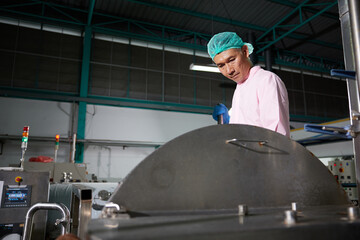 worker stirring water on large industrial pot in the factory