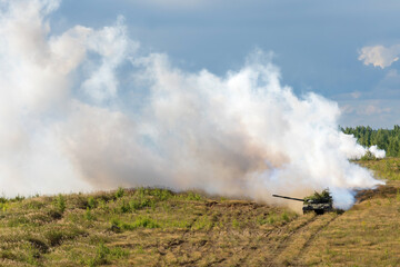 Heavy combat vehicles tanks drive around the butts and put up a smoke screen