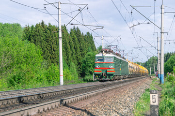 Naklejka premium The train is moving along the railway tracks. The tank car is pulled by two electric locomotives. Transportation of petroleum products by rail. Wagons with liquefied gas.