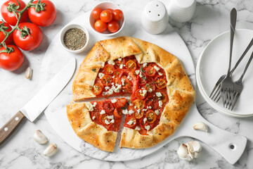Flat lay composition of tasty galette with tomato, thyme and cheese (Caprese galette) on white...