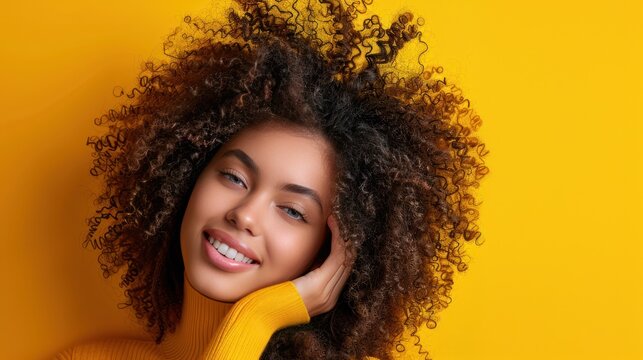 Portrait photo of a girl with curly hair waving, set against a vibrant yellow background