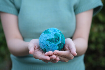 Earth Day In the hands holding green earth in dark Background. tree on ball. Saving environment, save clean planet ecology and environmentally sustainable. Save Earth, eco-friendly concept.