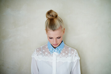 Woman, head and hairstyle with fashion for casual clothing on a beige wall background. Trendy, cool and female person with a blonde hair bun in fashionable or funky apparel and elegant aesthetic