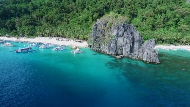 Seven Commandos and Papaya Beach in Palawan, Sightseeing Place. Tour A in El Nido, Philippines. Serene white sand beach with clear turquoise water, palm trees rock formations in Background. Drone