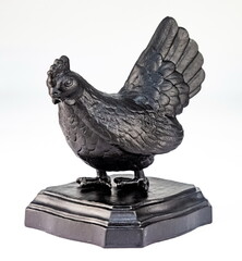 A purchased (consumer) cast iron chicken figurine in close-up on a white background