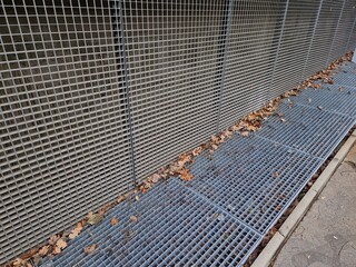 Ventilation grille along the house. basement windows are below ground level. Metal walking grid....
