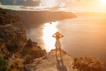woman sea travel. photo happy woman with hat in white dress standing on the shore on a hill...