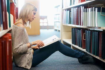 Woman, library and reading book on floor for studying education or university scholarship, learning...