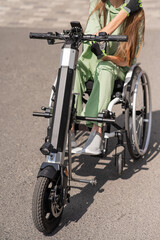 Fototapeta premium A woman in a wheelchair with an assistive device for manual control. Electric handbike. 