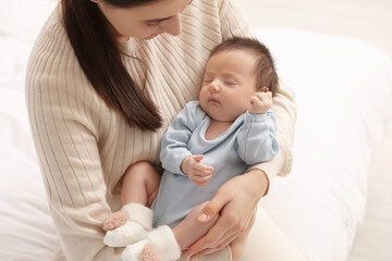 Mother with her sleeping newborn baby on bed at home, closeup