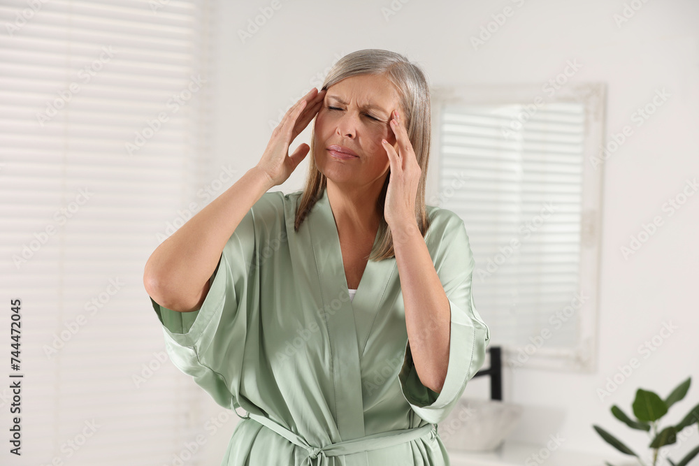 Poster Menopause. Woman suffering from headache in bathroom