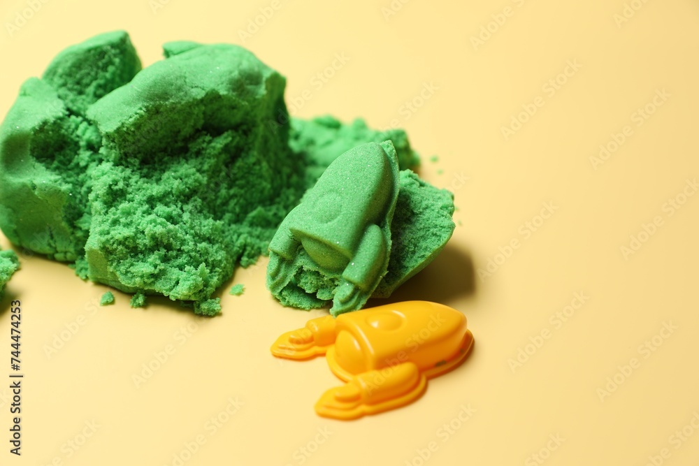 Poster Bright kinetic sand and plastic toys on beige background, space for text