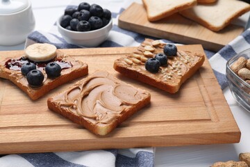 Different tasty toasts with nut butter and products on table, closeup