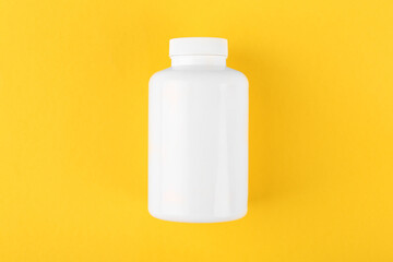 One white medical bottle on yellow background, top view