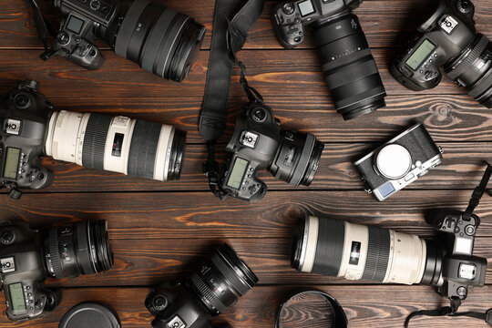 Modern cameras on wooden table, flat lay