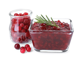 Tasty cranberry sauce in bowl and glass jar with fresh berries isolated on white