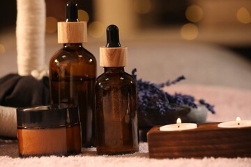 Composition with spa products and burning candles on soft light surface, closeup
