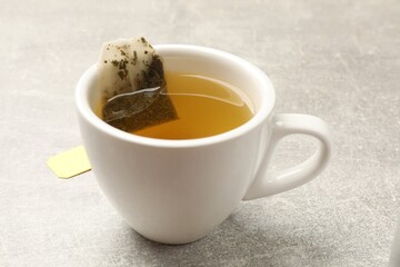 Brewing tea. Cup with tea bag on light table, closeup